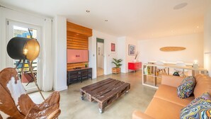 Una sala de estar moderna con un sofá, una mesa de centro, un televisor y un comedor con sillas.