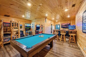 Ein Holzinterieur mit Billardtisch, Spielautomaten und Barhocker.