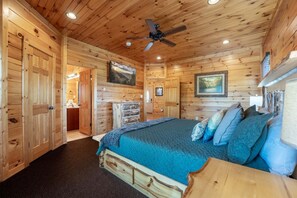 Ein Holzblockbau-Innenraum mit einem Bett, einem Deckenventilator und einem Kamin.