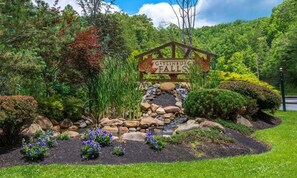 Schild für Gatlinburg Falls, umgeben von einem angelegten Garten mit Steinen und Blumen.