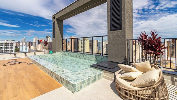 A rooftop terrace with a swimming pool, a lounge chair, and a view of the city skyline. - Edifício Morá (Curitiba)