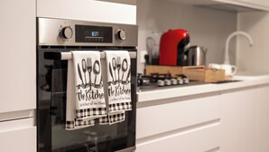A modern kitchen with a built-in oven, a digital clock, and a red kettle on the countertop. - From Kri•Modern design - 10 min Orio al Serio airport Bergamo - Self check in (Seriate)