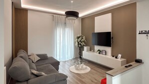 A modern living room with a grey sofa, a round glass coffee table, a white console table, and a red accent chair. - From Kri•Modern design - 10 min Orio al Serio airport Bergamo - Self check in (Seriate)
