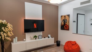 A modern living room with a flat-screen TV, a white console table, a red bean bag, and a potted plant. - From Kri•Modern design - 10 min Orio al Serio airport Bergamo - Self check in (Seriate)