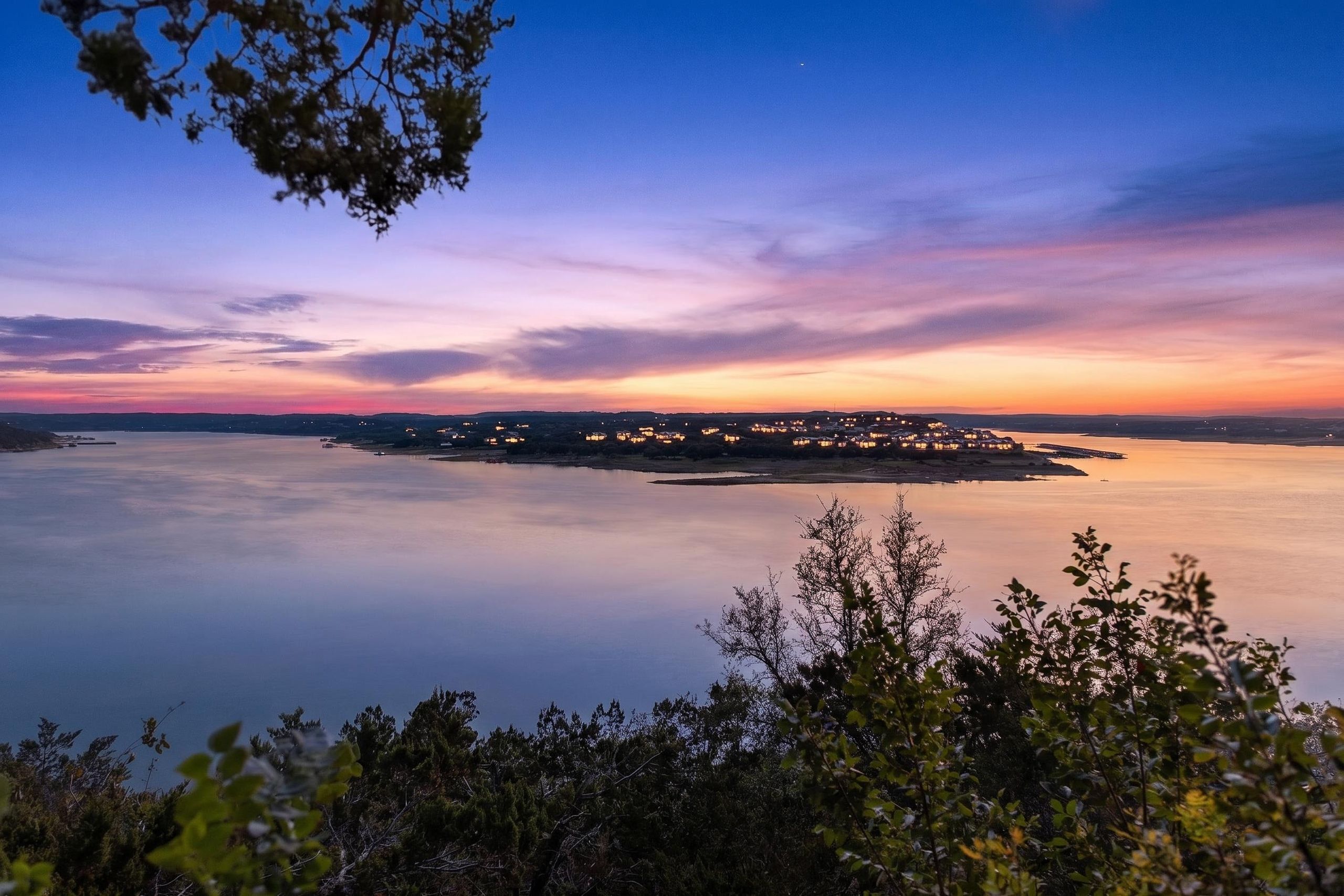 Un paysage côtier avec une mer calme, une petite île illuminée et un ciel dégagé.