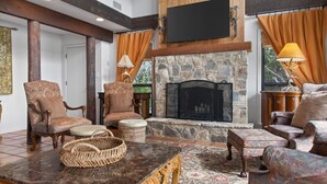 A cozy living room with a stone fireplace, wooden beams, and comfortable seating. - Lakefront Home w/Views, Huge Deck, Family-Friendly (Lago Vista)