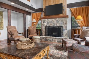 A cozy living room with a stone fireplace, wooden beams, and comfortable seating. - Lakefront Home w/Views, Huge Deck, Family-Friendly (Lago Vista)