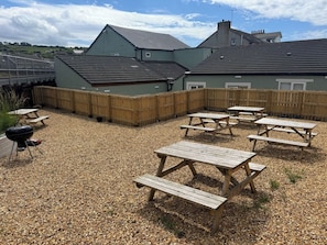 A backyard with picnic tables, a barbecue grill, and a wooden fence. - Station House – Platform 3 - 4 Bedrooms - Sleeps 6 (Harrington)