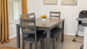 A dining table with four chairs, a vase with flowers, and artwork on the wall. - Enfilar Lane: Cozy Retreat Close to Stadiums & DFW (Arlington)