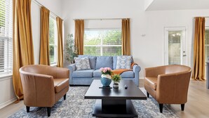 A living room with a sofa, two armchairs, a coffee table, and a window with curtains. - Enfilar Lane: Cozy Retreat Close to Stadiums & DFW (Arlington)