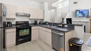 A modern kitchen with a built-in oven, dishwasher, and coffee station. - Enfilar Lane: Cozy Retreat Close to Stadiums & DFW (Arlington)