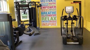 Une salle de sport équipée de matériel d’exercice, avec un mur d’inspiration et une horloge.