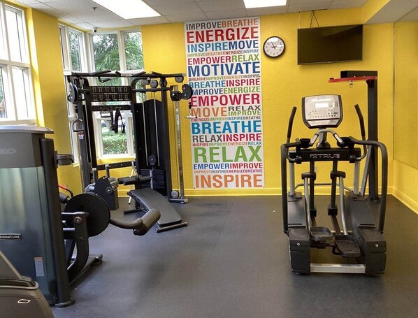 A gym with exercise equipment, a motivational wall, and a clock.