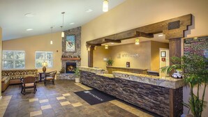 A reception area with a stone counter, wooden beams, a fireplace, and a sign for Wyndham. - Lake Tahoe | Alpine Lake Retreat | Pool + Lake (Zephyr Cove)