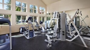 A gym with various exercise machines, large windows, and a high ceiling. - Lake Tahoe | Alpine Lake Retreat | Pool + Lake (Zephyr Cove)