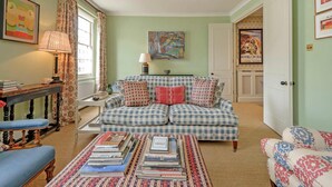 A cozy living room with a checkered sofa, a coffee table with books, a lamp, and a painting on the wall. - Gorgeous 3 Bedroom Flat - Pimlico (London)