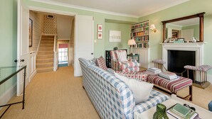 A living room with a sofa, armchairs, a fireplace, a bookshelf, and a staircase leading to another room. - Gorgeous 3 Bedroom Flat - Pimlico (London)