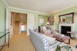 A living room with a sofa, armchairs, a fireplace, a bookshelf, and a staircase leading to another room. - Gorgeous 3 Bedroom Flat - Pimlico (London)