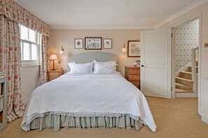 A bedroom with a bed, a nightstand, a lamp, a door, and a staircase. - Gorgeous 3 Bedroom Flat - Pimlico (London)