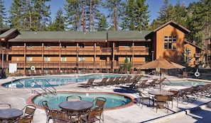 Ein Resort mit Poolbereich, Liegestühlen und einem Gebäude mit mehreren Balkonen.