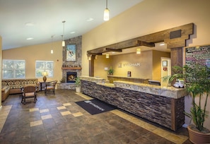A reception area with a stone counter, wooden beams, a fireplace, and a sign for Wyndham.