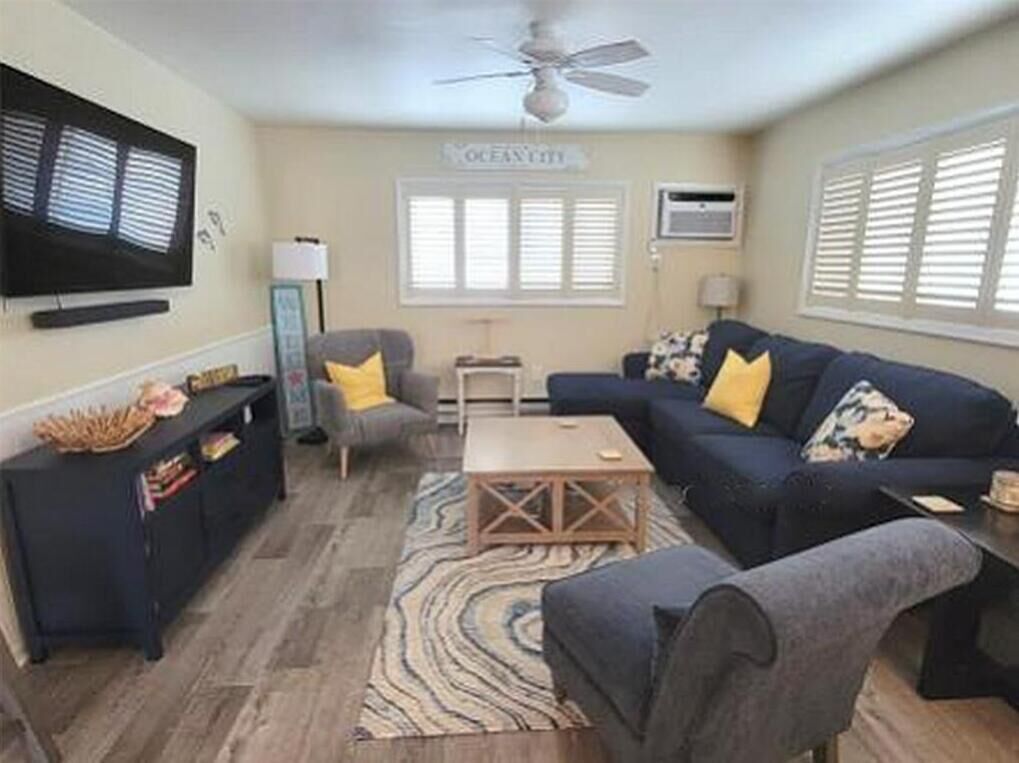 A living room with a sofa, armchair, coffee table, and television.