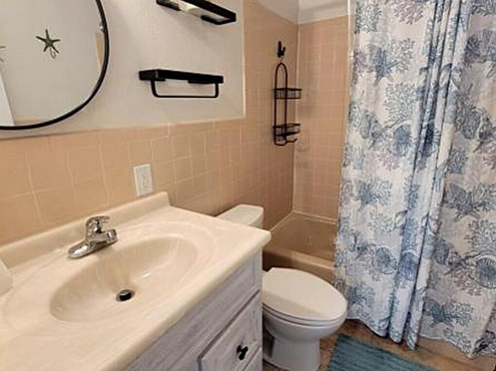 Un baño con lavamanos, inodoro y cortina de ducha.