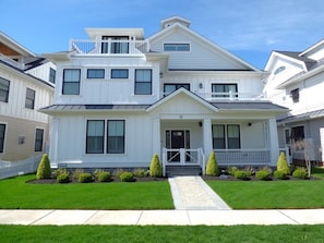 A two-story residential house with a front porch, a small balcony, and a well-maintained lawn. - Relaxing Shore Escape with PRVATE POOL-Close to Beach, Boards & Dining (Ocean City)