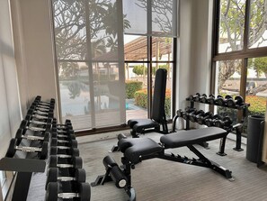 Uma academia com equipamentos de exercício, janelas amplas e vista para o exterior.