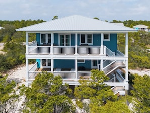 A two-story beach house with balconies, a metal roof, and surrounded by trees and sand. - Private Ft. Morgan Retreat / Sleeps 16 / Golf Cart (Gulf Shores)