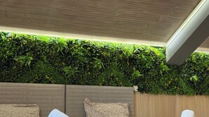 A modern hotel room with a green vertical garden wall, a large bed with patterned bedding, and neatly folded towels. - Vista Mare Sveti Vlas (Sveti Vlas)