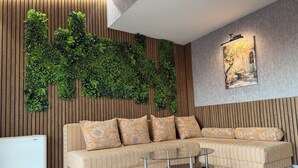 A modern living room with a sectional sofa, a glass coffee table, and a vertical garden wall. - Vista Mare Sveti Vlas (Sveti Vlas)