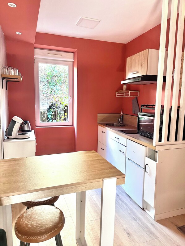 Une cuisine de taille réduite, avec une fenêtre, une table et une chaise.