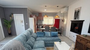 Un salon moderne avec un canapé d’angle, une table basse blanche et une cheminée.