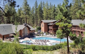 A resort with a pool, wooden buildings, and a forested backdrop. - Lake Tahoe | Alpine Group Retreat | Pool + Lake | 3BR Sleeps 8 (Zephyr Cove)