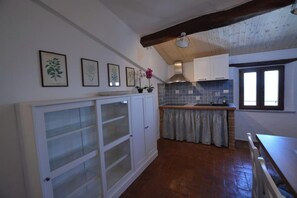 A kitchen with white cabinets, a tiled backsplash, and a wooden ceiling. - Panoramic apartment in medieval village (Radicondoli)