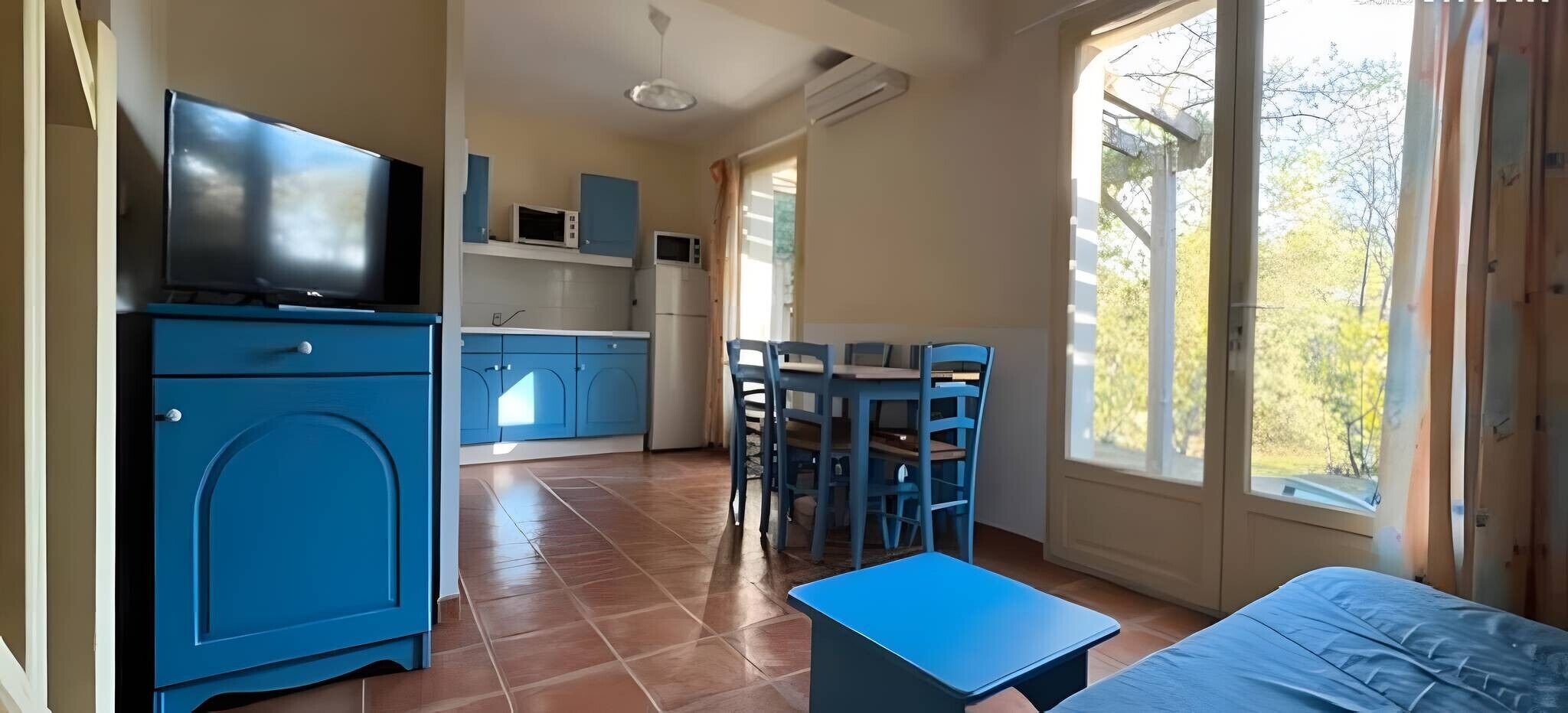 Une chambre de taille réduite équipée d’une télévision, d’un coin cuisine, d’un espace repas et d’un lit.