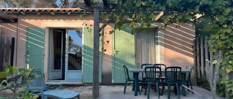 A small building with a door, a window, and a table with chairs outside.