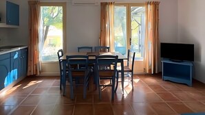 Un comedor con una mesa y sillas, un televisor y una zona de cocina con armarios.