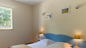 Ein Schlafzimmer mit einem Bett, zwei Nachttischlampen und drei gerahmten Bildern an der Wand.