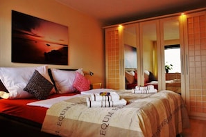 Ein Hotelzimmer mit Bett, einem großen Spiegel, einem Bild an der Wand und einem Kleiderschrank.