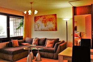 Ein modernes Wohnzimmer mit einer Couch, einem Glastisch, einer Lampe und einer Weltkarte an der Wand.