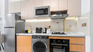 A modern kitchen with stainless steel appliances, a built-in oven, and a microwave. - Free Housekeeping Visits During Your Stay - Stayshort - Modern New Studio in Arjan That Sleeps 4 (Dubai)