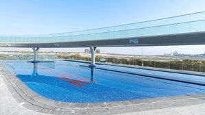 A swimming pool with a glass walkway overhead, surrounded by a paved area. - Free Housekeeping Visits During Your Stay - Stayshort - Modern New Studio in Arjan That Sleeps 4 (Dubai)