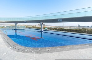 Ein Pool mit einem Glassteg darüber, umgeben von einem gepflasterten Bereich.
