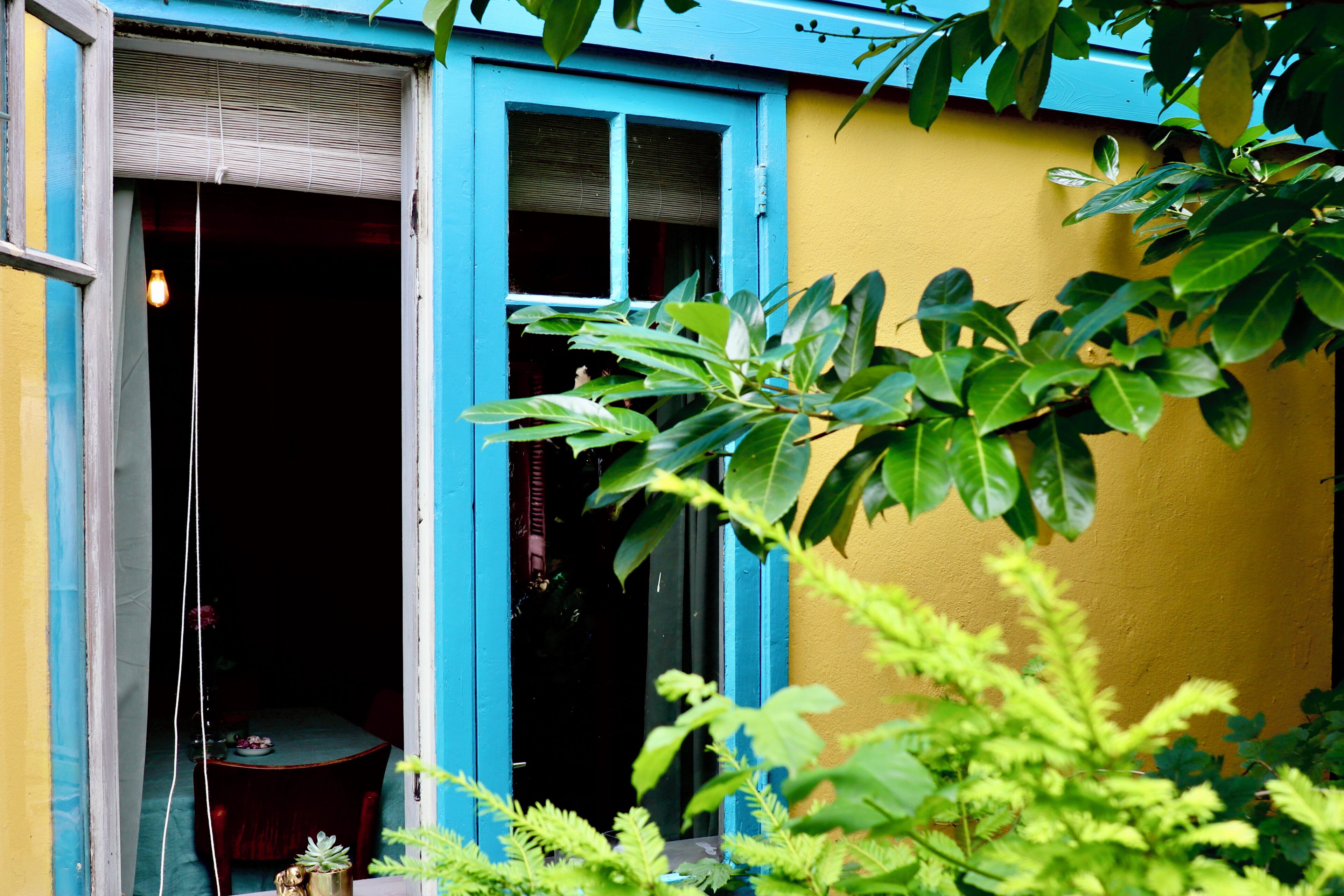 A room with a table and chairs, a window with blinds, and a door leading outside.