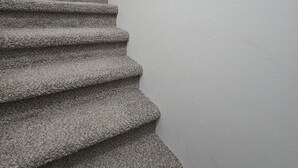 Una escalera con superficie texturizada que lleva a una puerta.