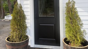 A black door with the number 201, two potted evergreen trees, and a wooden barrel doormat. - Hilltop Hideaway – Peaceful 2BR Suite, Near Beach Access and Mt. Baker Sunrises (North Saanich)