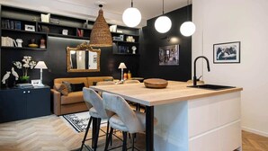 Una cocina moderna con una isla central, luces colgantes y un lavamanos empotrado.