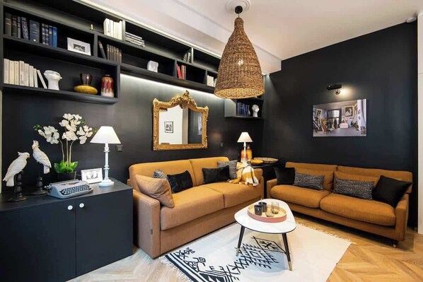 Una sala de estar moderna con un sofá, una mesa de centro, una estantería, un espejo y una lámpara colgante.